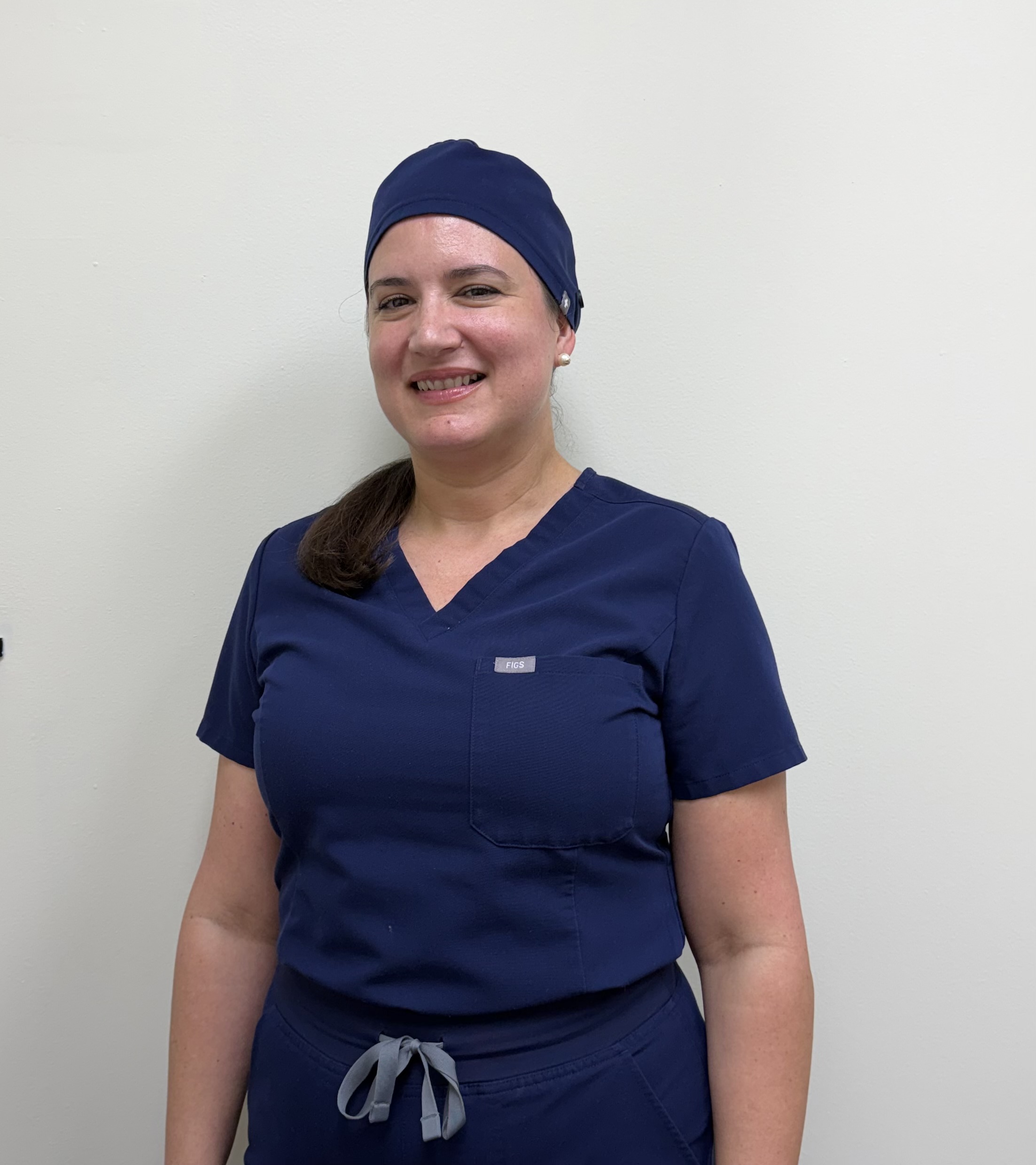 The image features a woman wearing a blue headscarf, white lab coat, and standing against a plain background.