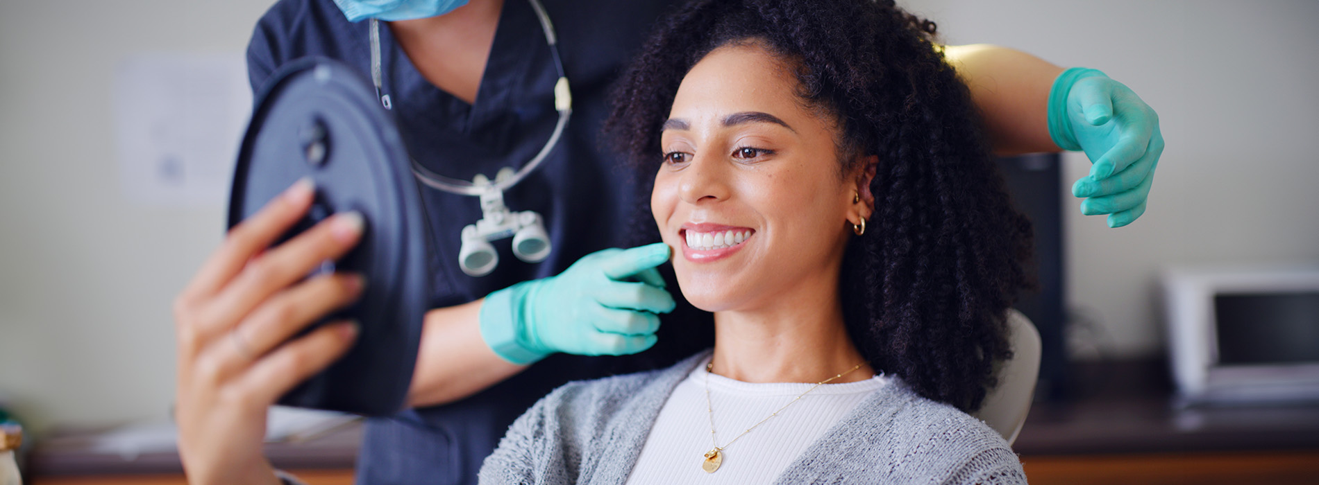 A woman receiving a haircut with a smiling expression while sitting in a salon chair.
