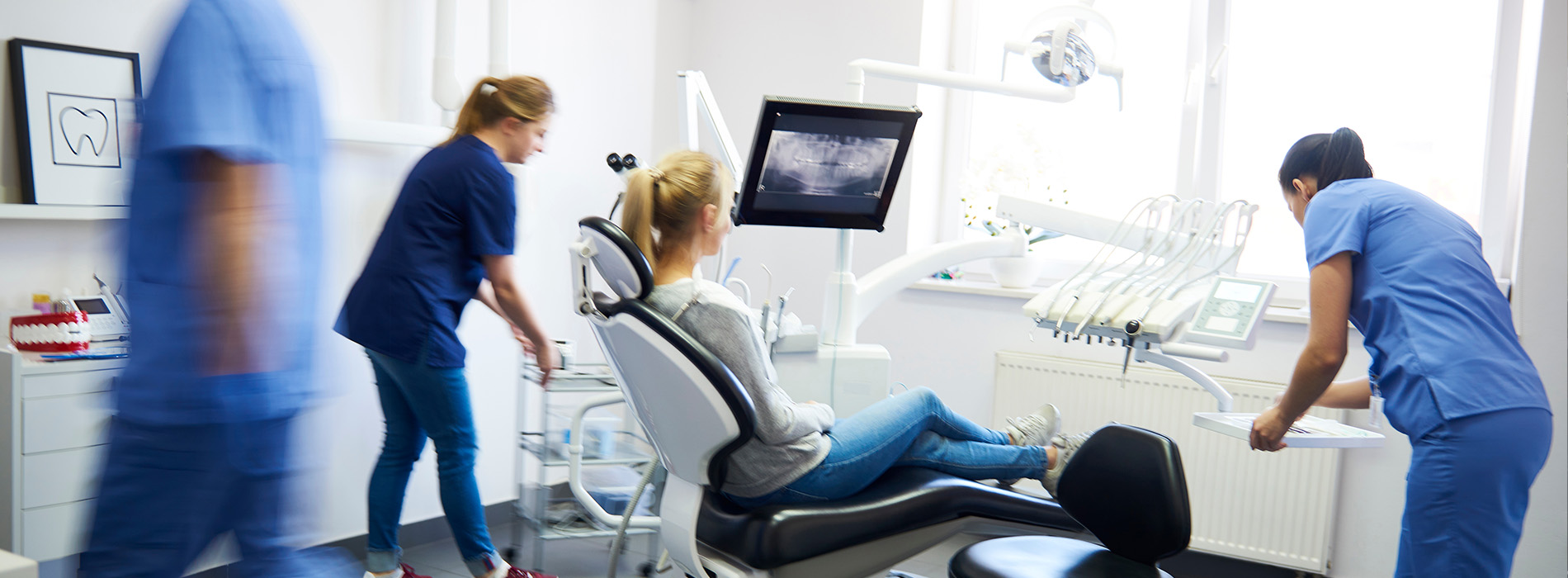 The image shows a group of healthcare professionals attending to patients in a medical setting, with various pieces of equipment visible around them.