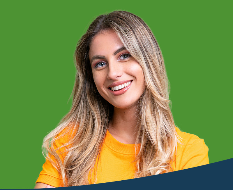 The image features a woman with long hair smiling at the camera, wearing a yellow top and standing against a green background.