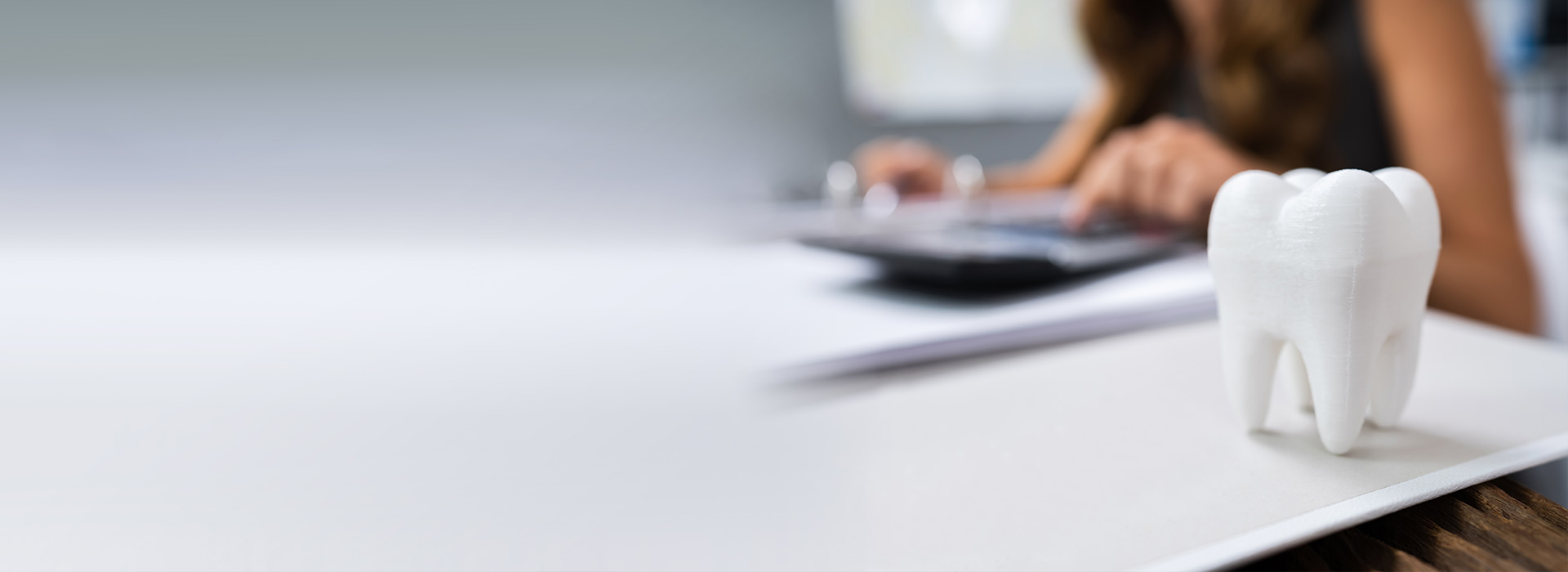 A person sitting at a desk with a laptop, working on a document, next to an object resembling a toothbrush.