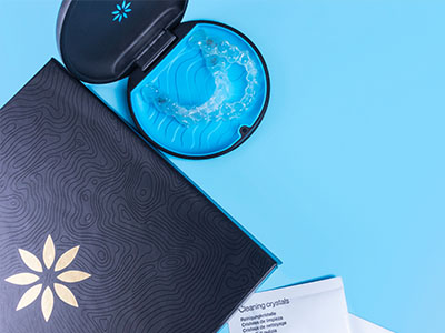 An image showing two cosmetic products with packaging on a blue surface, with a close-up view of a product inside its container and a small, round object resembling a lid nearby.
