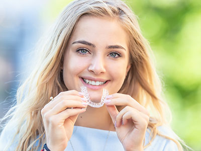 The image shows a young woman holding up a toothpaste tube with an open cap, displaying its contents, possibly for advertising or promotional purposes.