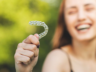 Woman holding up a toothbrush with C on it.