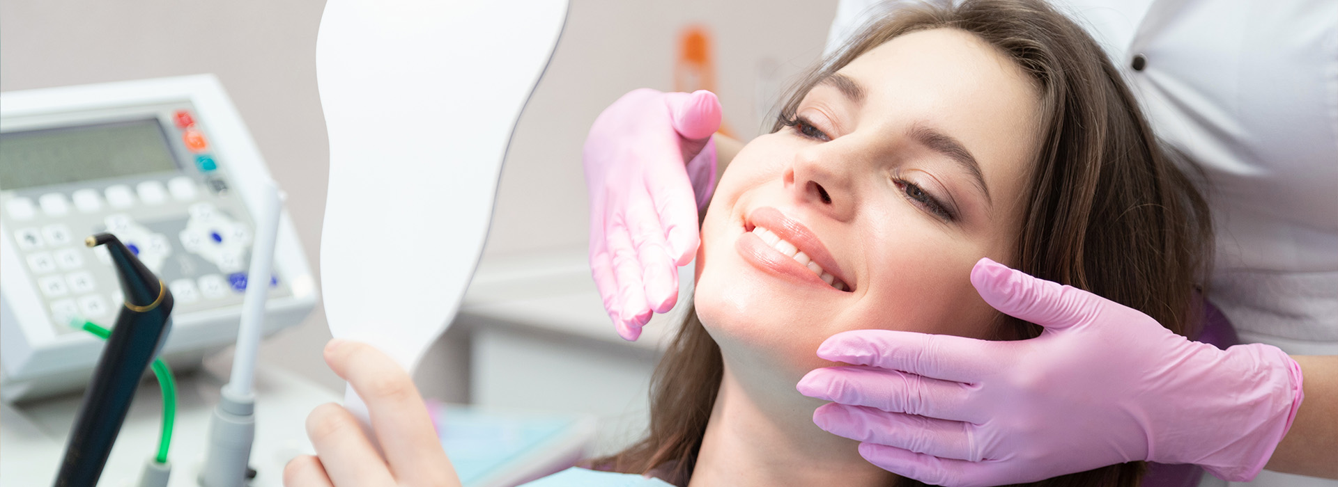 A woman receiving dental care with a dentist using a mirror to examine her mouth.