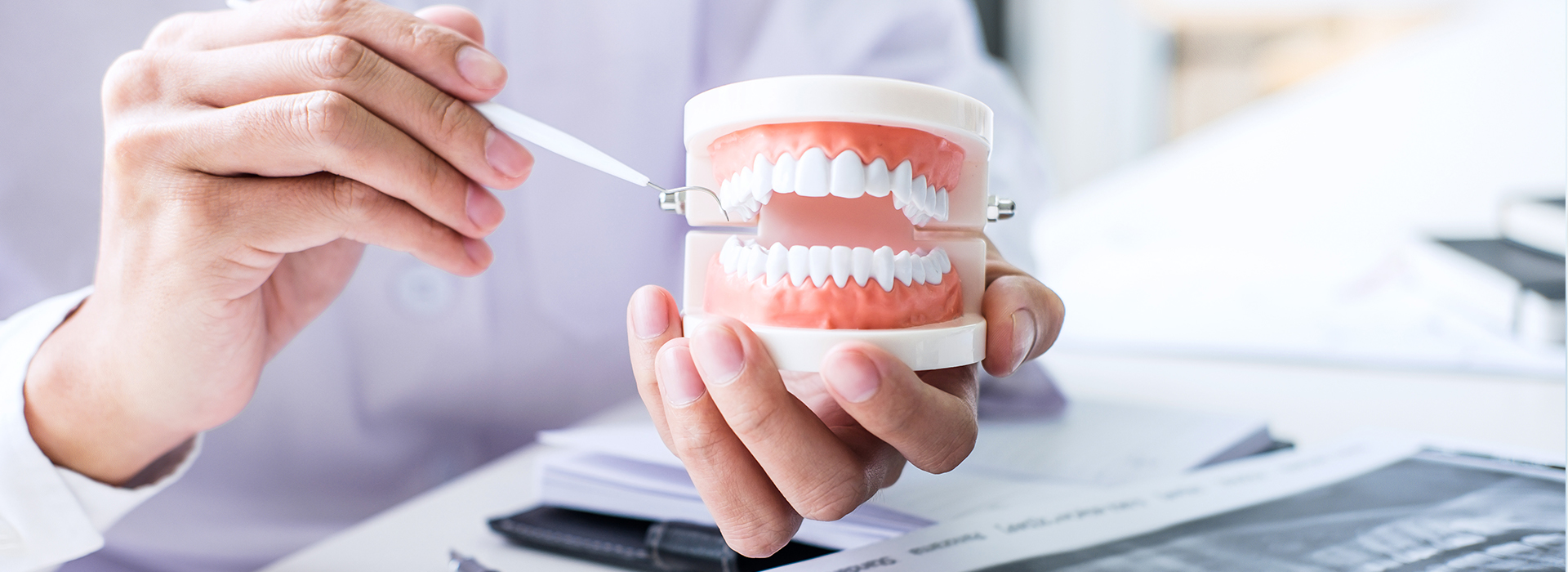 A person s hand holding a toothbrush with toothpaste over papers on a desk.