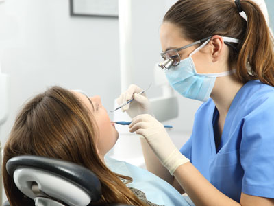 The image shows a dental hygienist performing a procedure on a patient s teeth while wearing personal protective equipment, with a focus on cleanliness and professionalism.