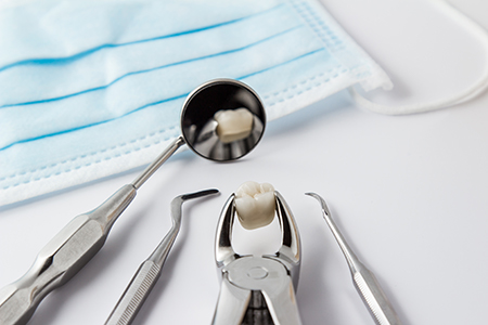 The image shows dental tools on a table with a blue surgical mask placed over them, emphasizing hygiene standards in a dental setting.