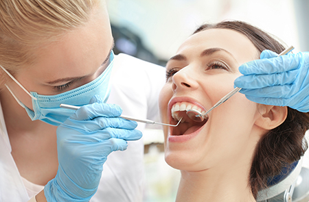 In the image, a dental hygienist is performing oral care on a patient, with both individuals wearing proper protective gear.