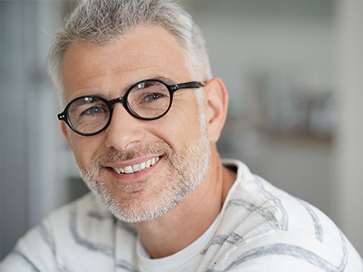 The image displays a man with glasses smiling at the camera, wearing a white shirt, with two different expressions on either side of a split-screen effect.