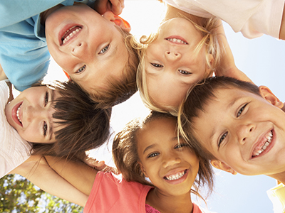 The image shows a group of children with different facial expressions, smiling and posing for the camera.